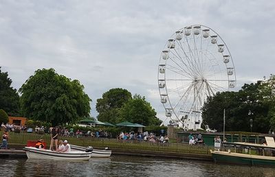 People on boat in river against cloudy sky