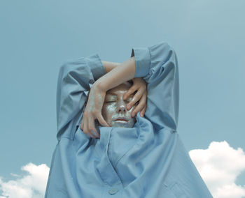 Midsection of woman holding umbrella against blue sky