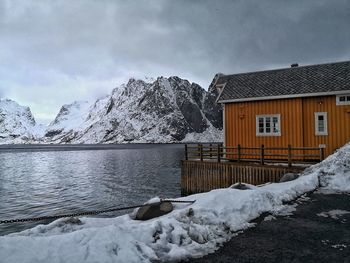 House by lake against sky during winter