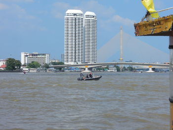 Nautical vessel on river in city against sky