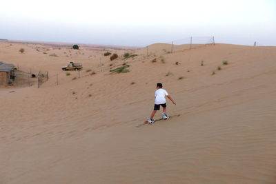 Rear view of boy boarding on desert