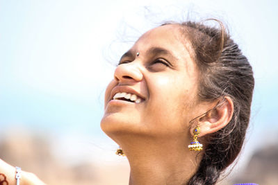 Close-up of teenage girl looking up against sky