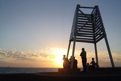 Silhouette of people on beach at sunset