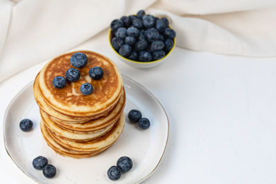 Stack of pancakes on plate with blueberries, top view