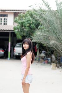 Full length of young woman standing against building