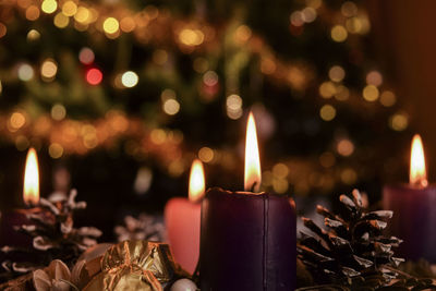 Close-up of illuminated candles by christmas decoration