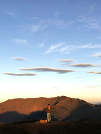 Rear view of woman standing on mountain against sky