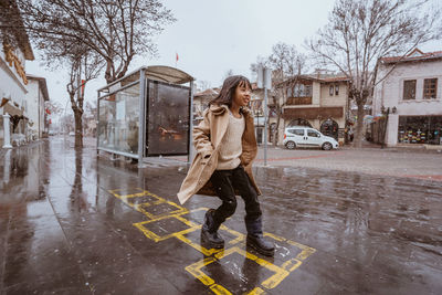 Full length of young woman standing in puddle
