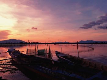 Boats moored in sea at sunset