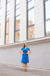 Full length portrait of woman standing against building in city
