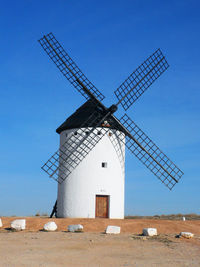 Traditional windmill on field against clear blue sky