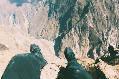 Low section of man sitting on rock