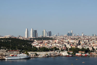 Sailboats in city by buildings against clear sky