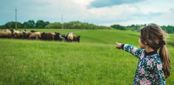 Girl pointing at flock of sheep