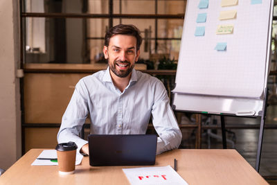 Young man using laptop while sitting on table