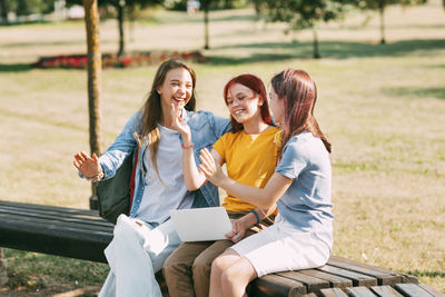 A group of teenage girls is sitting on a park bench and preparing for classes together