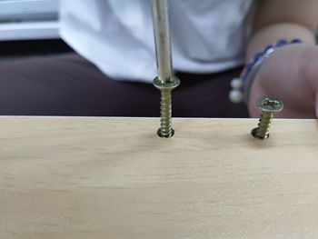 Midsection of man fixing screw in wooden table