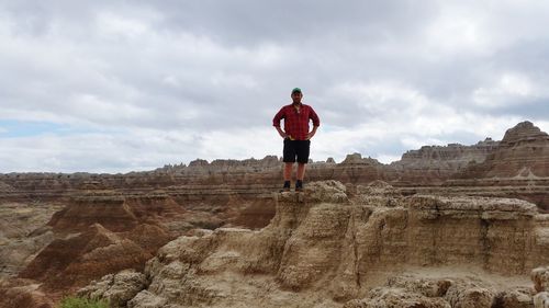 Rear view of man standing on rock against sky