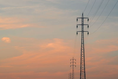 Low angle view of silhouette electricity pylon against sky during sunset