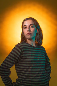 Portrait of young woman standing against yellow background