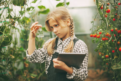Girl with a tablet in her hands examines a sample of a plant through a magnifying glass.organic pure