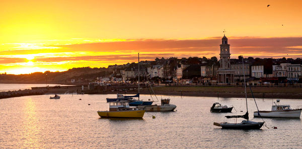 Boats in sea at sunset