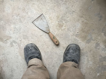 Low section of man standing by work tool on floor