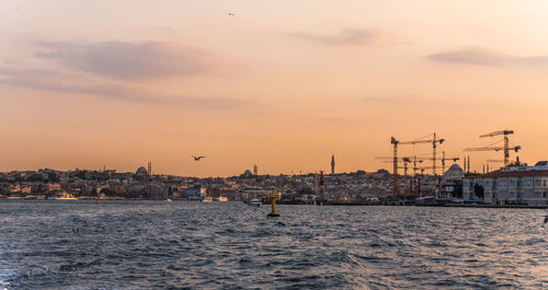 Scenic view of sea by buildings against sky during sunset