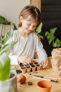 Girl planting seeds for seedlings in small recyclable peat pots, seedling container.spring gardening