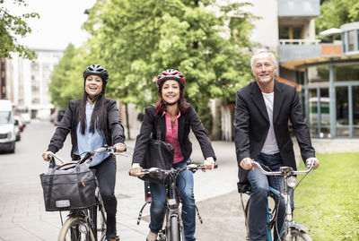 Happy business people riding bicycles on street