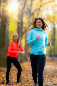Woman jogging, personal fitness trainer looking at a smart watch during training in the park.