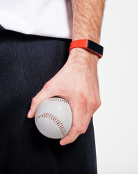 Midsection of man holding baseball against white background