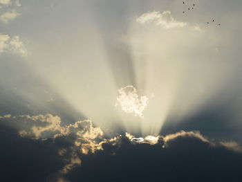 Low angle view of sun shining through clouds