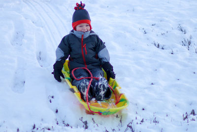 Boy sledding on snowy land