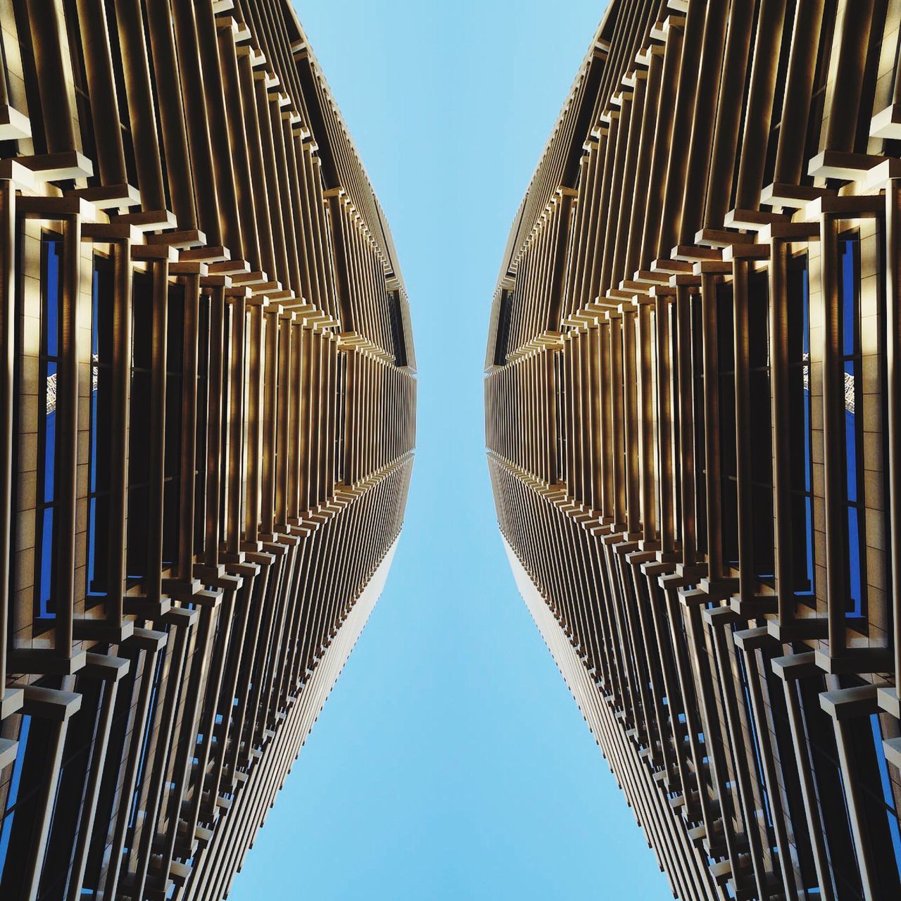 low angle view, architecture, built structure, clear sky, in a row, repetition, blue, building exterior, pattern, day, diminishing perspective, no people, outdoors, modern, tall - high, symmetry, building, sunlight, architectural column, travel destinations