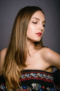 Beautiful young woman looking down against gray background