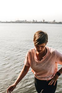 Young woman standing in sea against sky