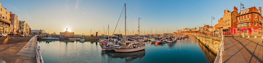 Boats moored at harbor against buildings in city