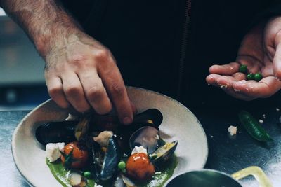 Cropped image of man preparing mussel in container