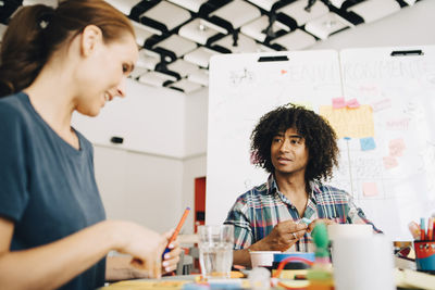 Multi-ethnic business colleagues discussing while working at table in creative office