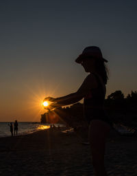 Silhouette girl at beach against sky during sunset