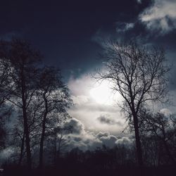 Low angle view of bare tree against cloudy sky