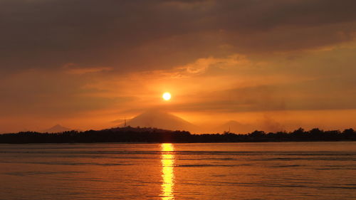 Scenic view of lake against cloudy sky during sunset