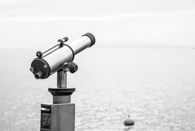 Coin-operated binoculars by sea against sky