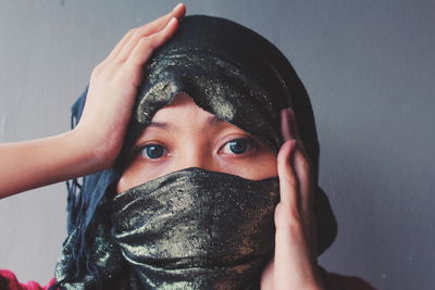 Close-up portrait of young woman wearing scarf against wall