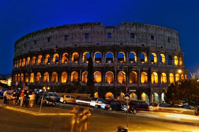 Blurred motion of tourists on street against coliseum during night