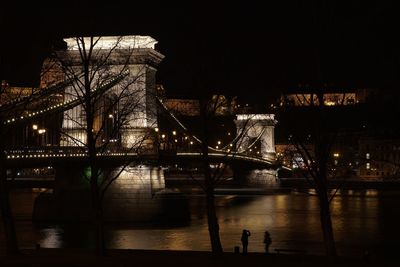 Illuminated bridge over river at night