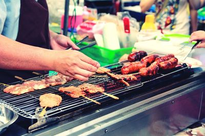 Close-up of man preparing food on barbecue grill