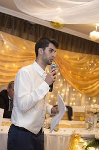 Young man looking at illuminated restaurant