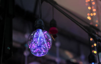 Low angle view of illuminated lighting equipment hanging at night